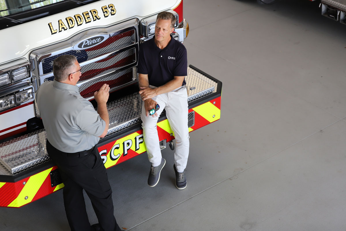 VFIS RD Erik Swanson talking while leaning on the hood of a ladder truck