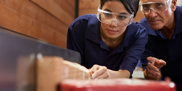 Workers running wood through tablesaw