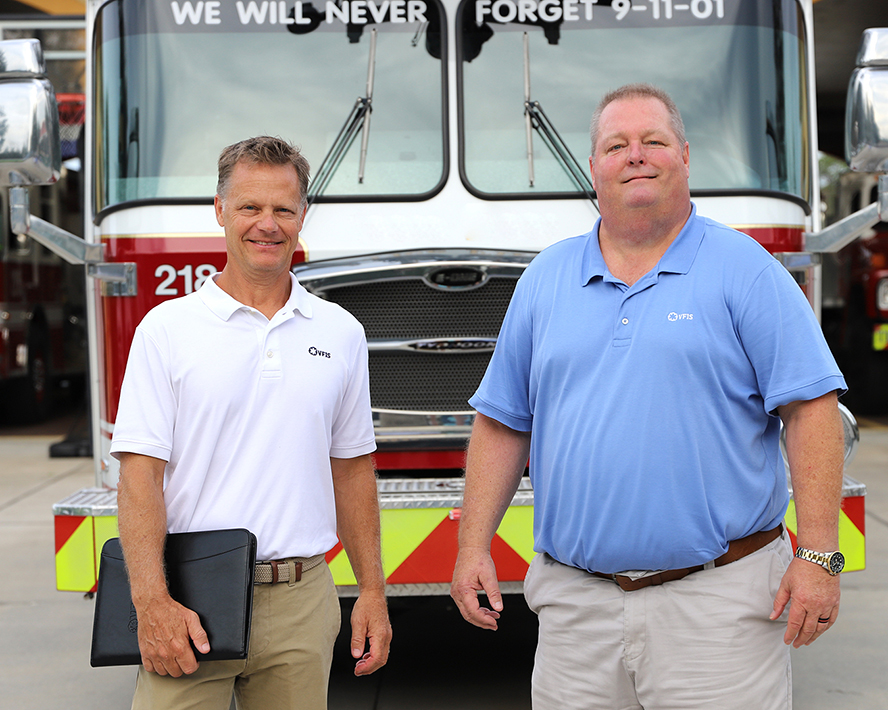 Erik and Russ smiling in front of a firetruck