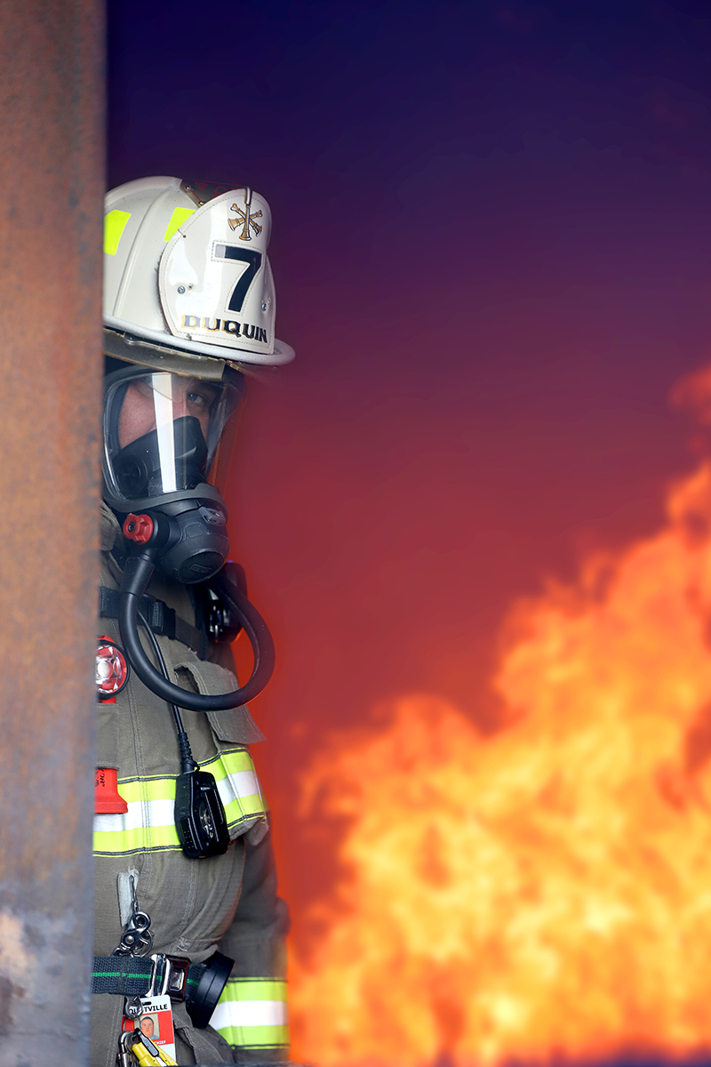 Bryan Duquin standing in a door with flames behind him